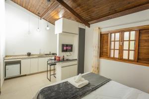 a kitchen with white cabinets and a bed in a room at Chalé Mantiqueira - Cunha in Cunha
