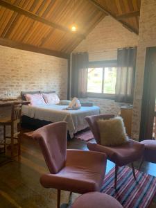 1 dormitorio con 1 cama y sillas en una habitación en Chalé na Av. Principal de Monte Verde com Lareira e Banheira, en Camanducaia