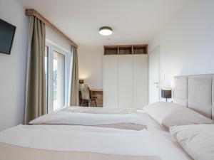 ein weißes Schlafzimmer mit 2 Betten und einem Fenster in der Unterkunft Ski-Nature Apartment Lungau in Mauterndorf