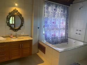 a bathroom with a tub and a sink and a shower curtain at Chalé na Av. Principal de Monte Verde com Lareira e Banheira in Camanducaia