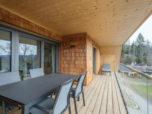 eine Holzterrasse mit einem schwarzen Tisch und Stühlen in der Unterkunft Ski-Nature Apartment Lungau in Mauterndorf