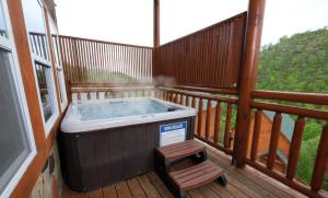 - un bain à remous installé sur une terrasse avec un tabouret dans l'établissement Splash Mountain Lodge, à Pigeon Forge