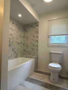 een badkamer met een wit bad, een toilet en een bad bij Charming 6BR 2 Ba Secluded Retreat walk to the shore in Long Branch
