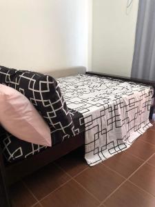 een bed met een zwart-witte deken erop bij Kasara Urban Resort and Residences in Manilla