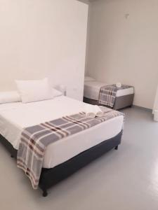 Duas camas num quarto com paredes brancas em Aloja-T en Apartamento amoblado 6 con balcón Ciudad Bolivar em Ciudad Bolívar