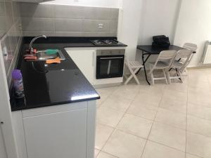 cocina con encimera negra y mesa en appartement plage petit paradis 