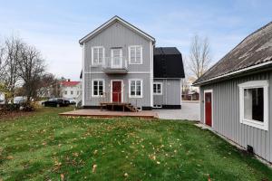 una casa gris con una puerta roja y un patio en Guestly Homes - 4BR Charming Apartment, en Piteå