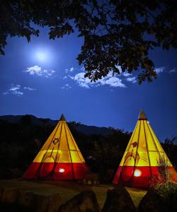 two colored tents in a field at night at BIOSFERA LODGE GLAMPING tipi 2 personas in Oxapampa