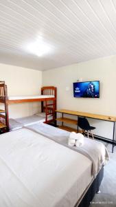 two beds in a room with a tv on the wall at Pousada Siriba in Caravellas