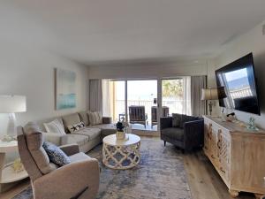 a living room with a couch and a tv at Driftwood Towers #1F - Palm View in Gulf Shores