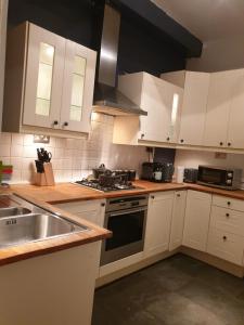 a kitchen with white cabinets and a stove top oven at Derby rooms by Peartree in Derby