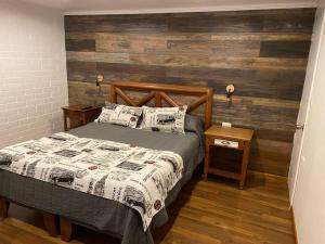 1 dormitorio con 1 cama y pared de madera en Lindo Apartamento, full equipado -Factura empresas-, en Quillota