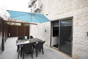 a table and chairs with a blue umbrella on a patio at Naylover Hotel Suites in Amman