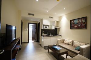 a living room with a couch and a tv and a kitchen at Naylover Hotel Suites in Amman