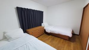 a small room with two beds and a dresser at Iruma INN in Minamiizu