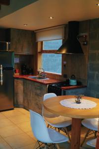 a kitchen with a wooden table with chairs and a sink at Origen Rent a house in El Bolsón