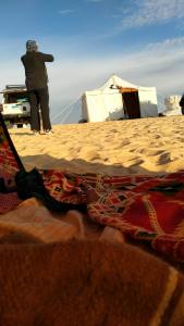 eine Person, die am Strand neben einem Zelt steht in der Unterkunft Egypt white and black desert with Camping in Az Zabū