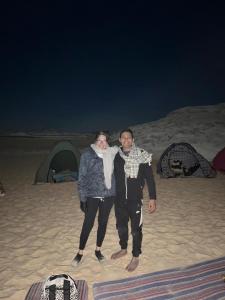 un homme et une femme debout sur la plage la nuit dans l'établissement Egypt white and black desert with Camping, à Az Zabū
