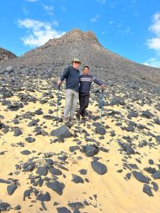 two people standing on a beach with rocks at Egypt white and black desert with Camping in Az Zabū