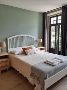 um quarto com uma cama branca, 2 candeeiros e uma janela em Villa Dos Santos - Gerês Country House no Gerês