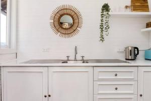 a white kitchen with a sink and a mirror at Newly Reburbished Sydney Harbourfront Boathouse Escape in Sydney