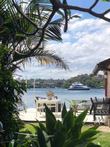 a patio with a table and a boat in the water at Newly Reburbished Sydney Harbourfront Boathouse Escape in Sydney
