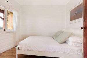 a white room with a bed with a window at Newly Reburbished Sydney Harbourfront Boathouse Escape in Sydney