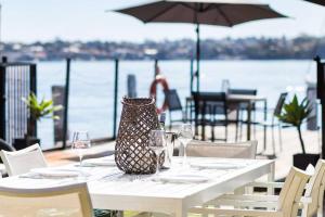 a table with wine glasses and a vase sitting on it at Newly Reburbished Sydney Harbourfront Boathouse Escape in Sydney