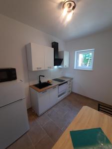 a small kitchen with white cabinets and a table at Appartements Lena. in Premantura