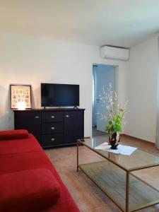een woonkamer met een rode bank en een tv bij Appartements Lena. in Premantura