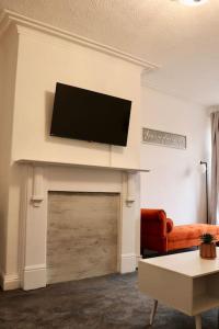 een woonkamer met een flatscreen-tv boven een open haard bij Charming 3 Bedroom Property FREE WiFi & Parking in Beeston