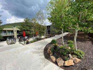 un jardin avec des arbres et des rochers devant un bâtiment dans l'établissement Premier Ski & City Escape: Upscale 2BR Condo in Downtown Park City, à Park City