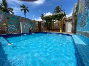 a large swimming pool with a mural on the side of a building at Chalé Palhano Beach in São Miguel dos Milagres