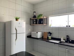 a kitchen with a white refrigerator and a window at Casa 3 suítes com piscina in Natal