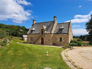 ein altes Steinhaus auf einem grünen Rasen in der Unterkunft Breton granite stone house with fantastic sea views in Saint-Pol-de-Léon