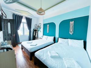 two beds in a room with blue walls at Mon-Min Hotel in Da Lat