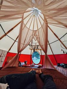 a person laying on a bed in a tent at Biosfera Lodge tipi para 3 personas in Oxapampa