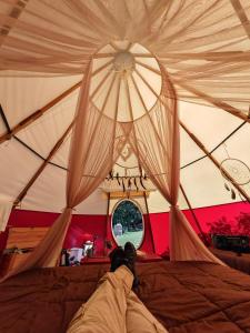 a person laying on a bed in a tent at Biosfera Lodge tipi para 3 personas in Oxapampa