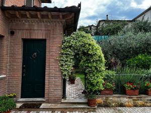 uma porta verde numa casa de tijolos com plantas em Nonna Lella - Appartamento con parcheggio privato em Montepulciano