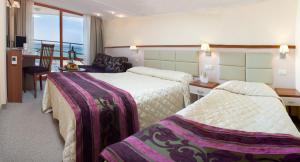 a hotel room with two beds and a desk at Kaliakra Beach Hotel - Ultra All Inclusive in Albena