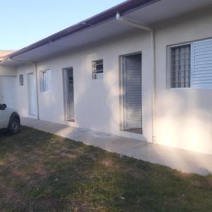 Una casa blanca con un coche aparcado delante. en Bela Vista Suítes, en Campos do Jordão