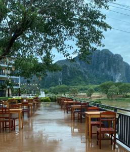 a row of tables and chairs in the rain at Lisha The Grand Riverside Hotel in Vang Vieng