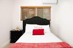 a bedroom with a bed with a red pillow on it at Sheer Bliss BeachView Apt #1 in Georgetown