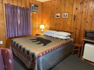 a bedroom with a bed in a room with wooden walls at Cedars Motel in Saint Ignace