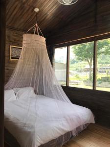 a bed with a net on it in a room with windows at Little Ta Van Homestay in Sa Pa