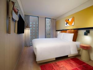 ソウルにあるMoxy Seoul Myeongdongのベッドルーム(白いベッド1台、大きな窓付)