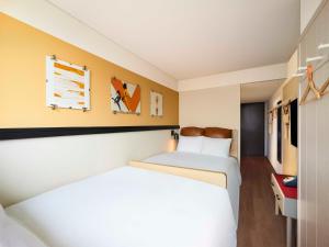 a hotel room with two beds and yellow walls at Moxy Seoul Myeongdong in Seoul