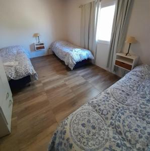 um quarto com 2 camas e piso em madeira em Finca La Calma em São Rafael