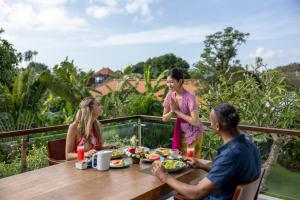 a group of people sitting around a table eating food at Villa UmaDahayu in Sanur
