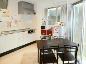 a kitchen with a table and chairs and a refrigerator at Guest House Ochakare in Kanazawa